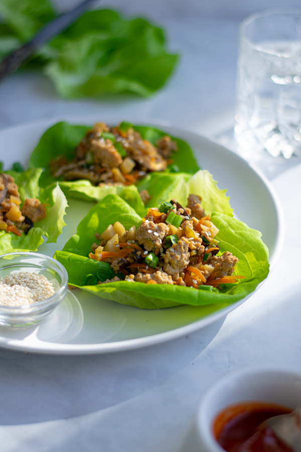 Lettuce wrap with ground chicken on a plate, the direct sunlight is lighting up a single lettuce wrap.