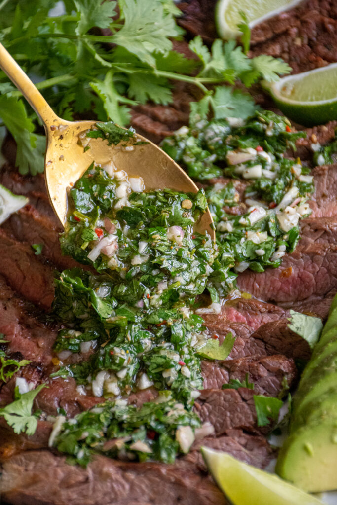 Chimichurri spooned onto a steak.