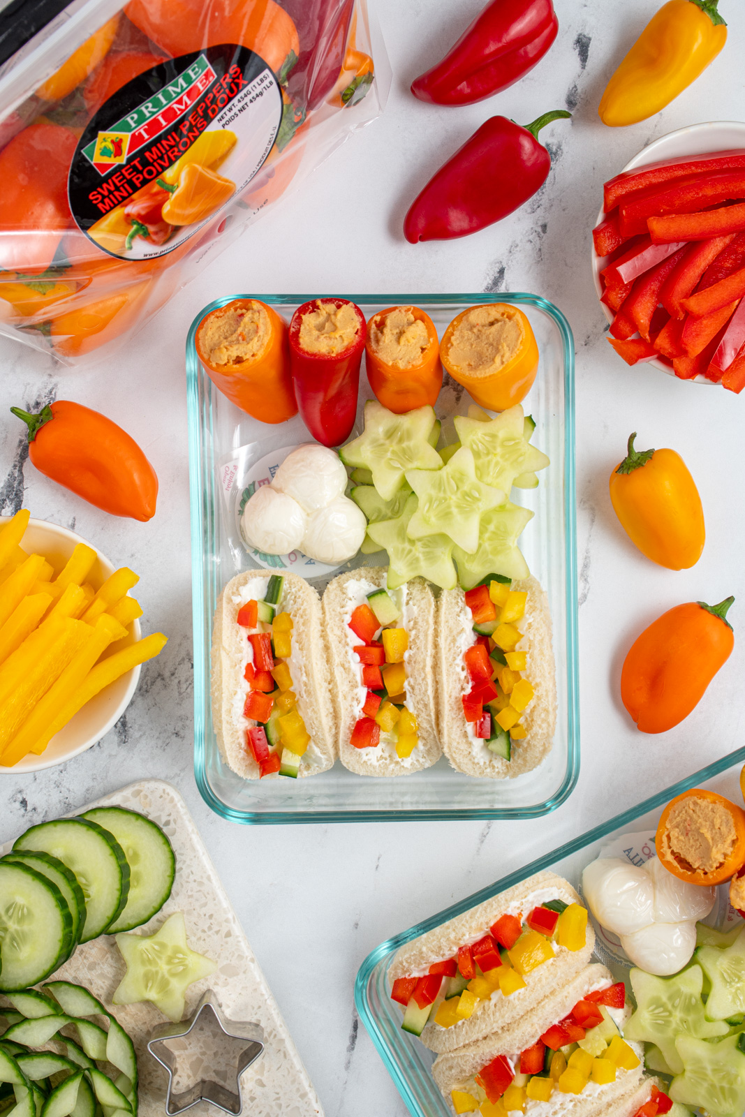 A snack container with mini sandwiches and veggies.